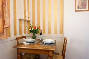 Una mesa de comedor preparada con platos, vasos y una botella, con una pared a rayas y un cuadro enmarcado al fondo.