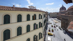 A street view with buildings, a yellow taxi, and a dome structure in the background. - Apartments Florence - Ariento Eva 1bdr San Lorenzo (Firenze)