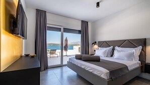 Et moderne hotelværelse med en stor seng, et fjernsyn og havudsigt.