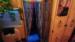 A cozy room with a wooden door, a small window, and a welcome mat. - Boho Caravan themed, Vintage 1961 Oasis Camper (Monroe)