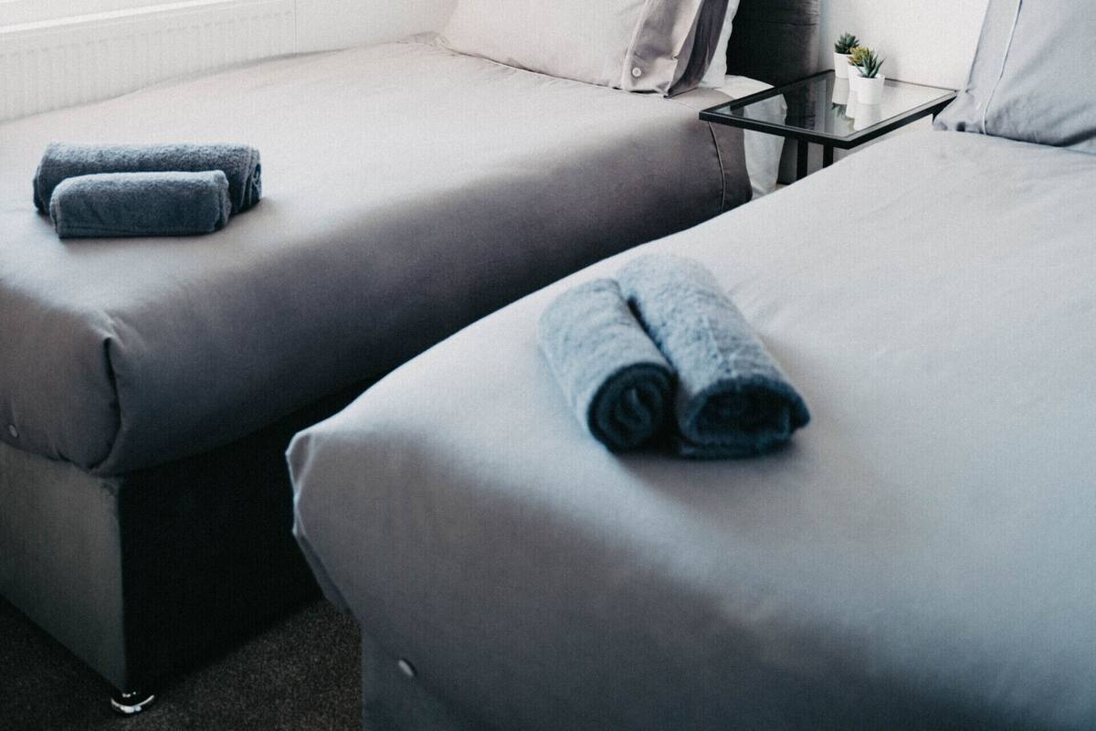 Ein Hotelzimmer mit zwei Einzelbetten, einem kleinen Tisch mit einer Pflanze und einer Hängelampe.