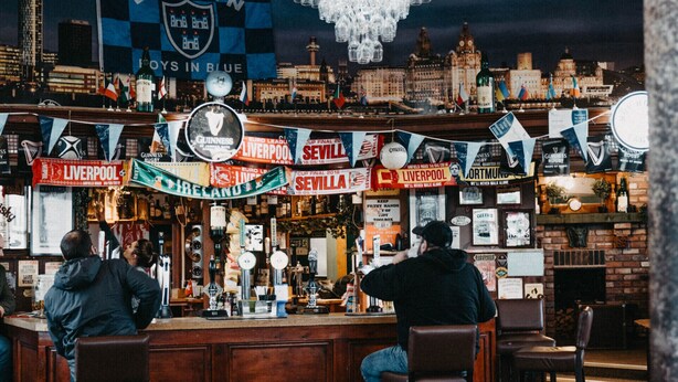 Un bar décoré d’une fresque représentant un paysage urbain, doté de meubles en bois et d’un lustre.