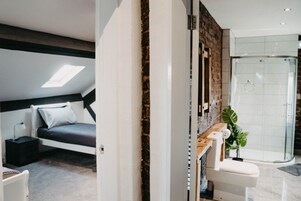Un dormitorio moderno con tragaluz, zona de ducha separada y una mesita de noche pequeña.
