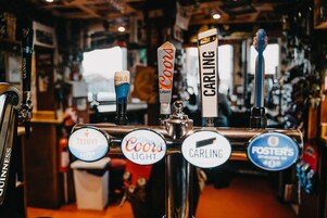 A bar with multiple beer taps labeled with brands like Guinness, Coors Light, Carling, and Foster's.