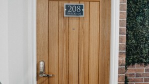 Une porte en bois avec une plaque portant le numéro « 208 » et une poignée en métal.