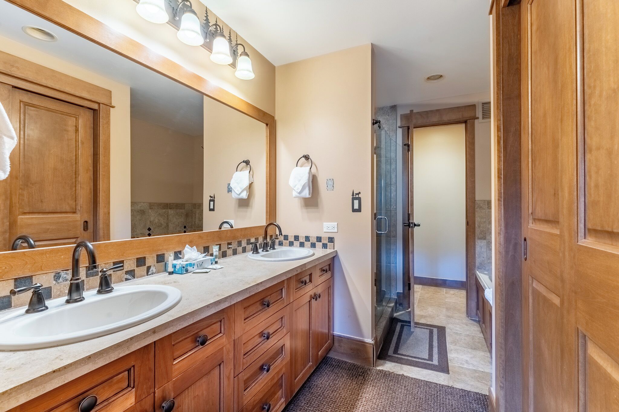 A bathroom with two sinks, a large mirror, and a shower area.