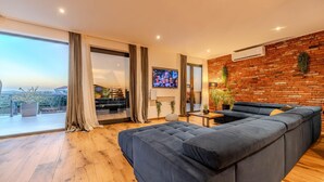 Ein modernes Wohnzimmer mit einem großen Ecksofa, einem Flachbildfernseher und einer Ziegelwand.