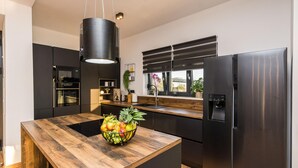 Eine moderne Küche mit einer Holzinsel, Edelstahlgeräten und einem Fenster mit Jalousien.