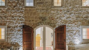 A stone building with arched wooden doors and multiple windows. - Villa Mediterranean Estate (Uskoplje)