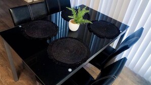 Una mesa de comedor con cuatro individuales negros, una planta en maceta y sillas negras.