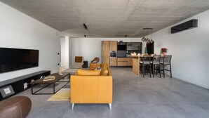 A modern living room with a sofa, a coffee table, and a TV. There is a kitchen area with a dining table and chairs. - 3 bedroom awesome home in Labin (Labin)