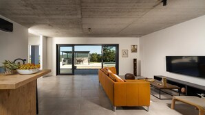 A modern living room with a sofa, a TV, and a dining area with a bowl of fruit. - 3 bedroom awesome home in Labin (Labin)