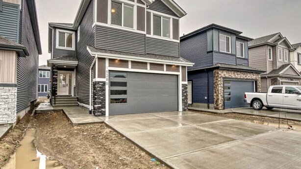 A two-story residential house with a garage, a driveway, and a white pickup truck parked in front. - Kozy In Keswick (Suite) (Edmonton)