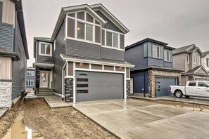 A two-story residential house with a garage, a driveway, and a white pickup truck parked in front. - Kozy In Keswick (Suite) (Edmonton)