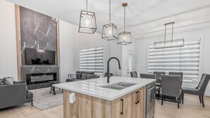 A modern kitchen with a central island, a built-in sink, and a dining area with chairs. - Kozy In Keswick (Upper Suite) (Edmonton)