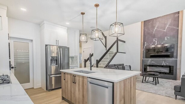 A modern kitchen with a central island, stainless steel appliances, and a built-in oven. - Kozy In Keswick (Upper Suite) (Edmonton)