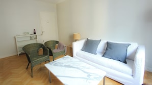 A living room with a white sofa, two armchairs, a small table, and a lamp. - Amplio y Silencioso en Recoleta Luz (Buenos Aires)