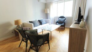 A modern living room with a sofa, two chairs, a coffee table, a lamp, and a television on a wooden cabinet. - Amplio y Silencioso en Recoleta Luz (Buenos Aires)