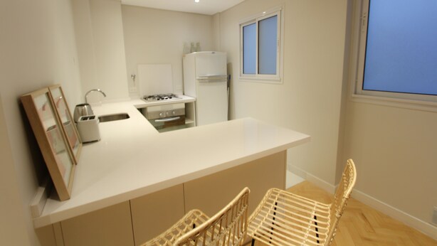 A modern kitchen with a central island, built-in appliances, and a window with blinds. - Amplio y Silencioso en Recoleta Luz (Buenos Aires)