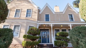A two-story house with a symmetrical facade, a central entrance with a blue door, and a small porch with white railings.