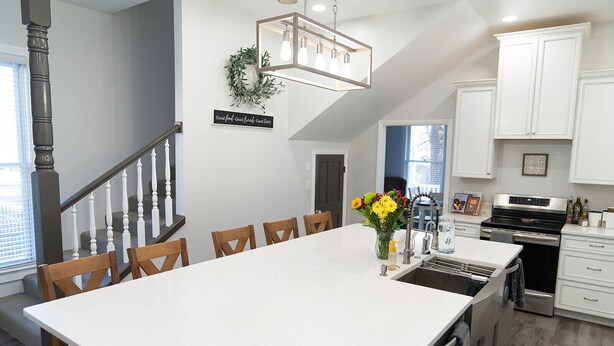 A modern kitchen with white cabinetry, a large island, and a dining area with wooden chairs.