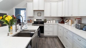 A modern kitchen with white cabinetry, a stainless steel oven, and a built-in dishwasher.