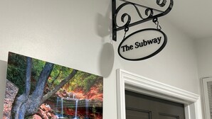 Eine Wand mit einem gerahmten Gemälde eines Wasserfalls und einem Schild mit der Aufschrift 'The Subway'.