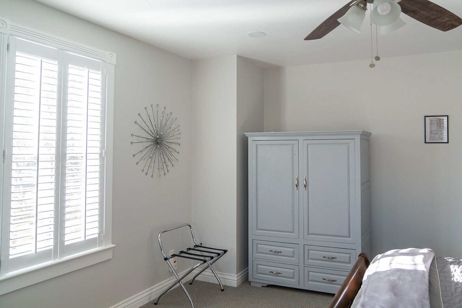 A bedroom with a bed, a wardrobe, a radiator, and a window with blinds.