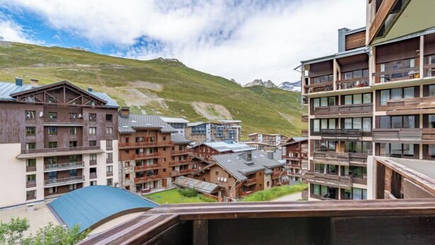 Et hotel med flere etager, balkoner og et bjerglandskab i baggrunden.