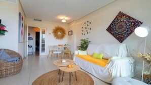 Ein modernes Wohnzimmer mit einem weißen Sofa, einem Esstisch und einem Korbstuhl.