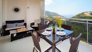 Ein Balkon mit Esstisch für zwei Personen, einer Couch und einer Sonnendekoration an der Wand.