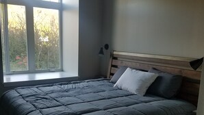 A bedroom with a bed, a window, and a nightstand.