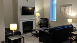 A living room with a fireplace, a television, a sofa, and a ceiling fan.