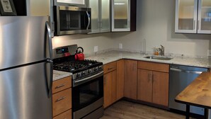 A modern kitchen with stainless steel appliances, wooden cabinets, and a granite countertop.