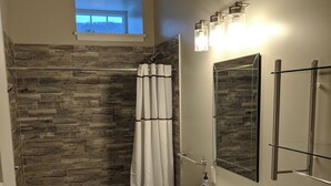 A bathroom with a shower, a sink, a toilet, and a window.