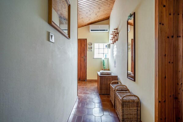 A hallway with hexagonal tiles, wicker baskets, wooden walls, and a ceiling with wooden beams.