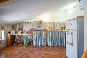 A compact kitchen with a tiled backsplash, a refrigerator, a gas stove, and a sink. - GuestHost - Torre di Calasetta Cozy Apartment (Calasetta)