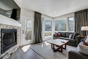 Relax in this cozy living space with a fireplace, forest views, and comfortable seating for guests.