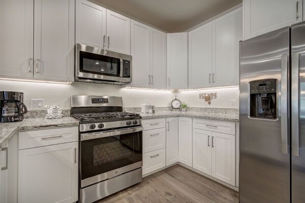 Enjoy cooking in this well-equipped kitchen with stainless steel appliances, white cabinetry, and granite countertops.
