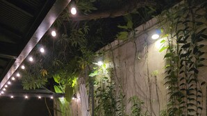 An outdoor seating area with tables and chairs, surrounded by lush greenery and decorative lighting. - Hotel Rilux Cartagena (Cartagena)