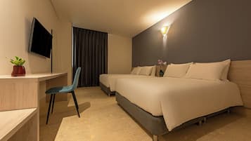 Una habitación de hotel con cama, escritorio, silla, televisor y lámpara de pared.