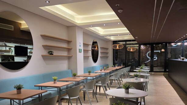 A modern restaurant with a long counter, round tables, and blue cushioned seating. - Hotel Rilux Cartagena (Cartagena)