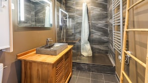 Une salle de bain moderne avec un meuble-lavabo en bois, une cabine de douche en verre et un porte-serviettes.