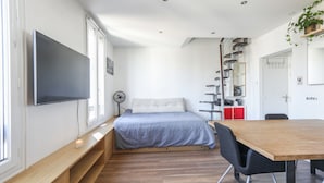 Une chambre moderne comprenant un lit, une table de chevet, un téléviseur et un bureau avec une chaise.
