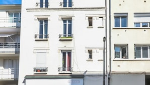 Un immeuble à plusieurs étages doté de balcons, avec une devanture visible et une voiture garée devant.