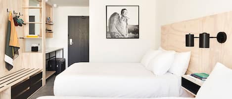 Une chambre d’hôtel avec deux lits, un bureau, une armoire et une lampe fixée au mur.
