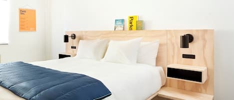 A modern bedroom with a bed, bedside tables, and a wall-mounted light fixture.