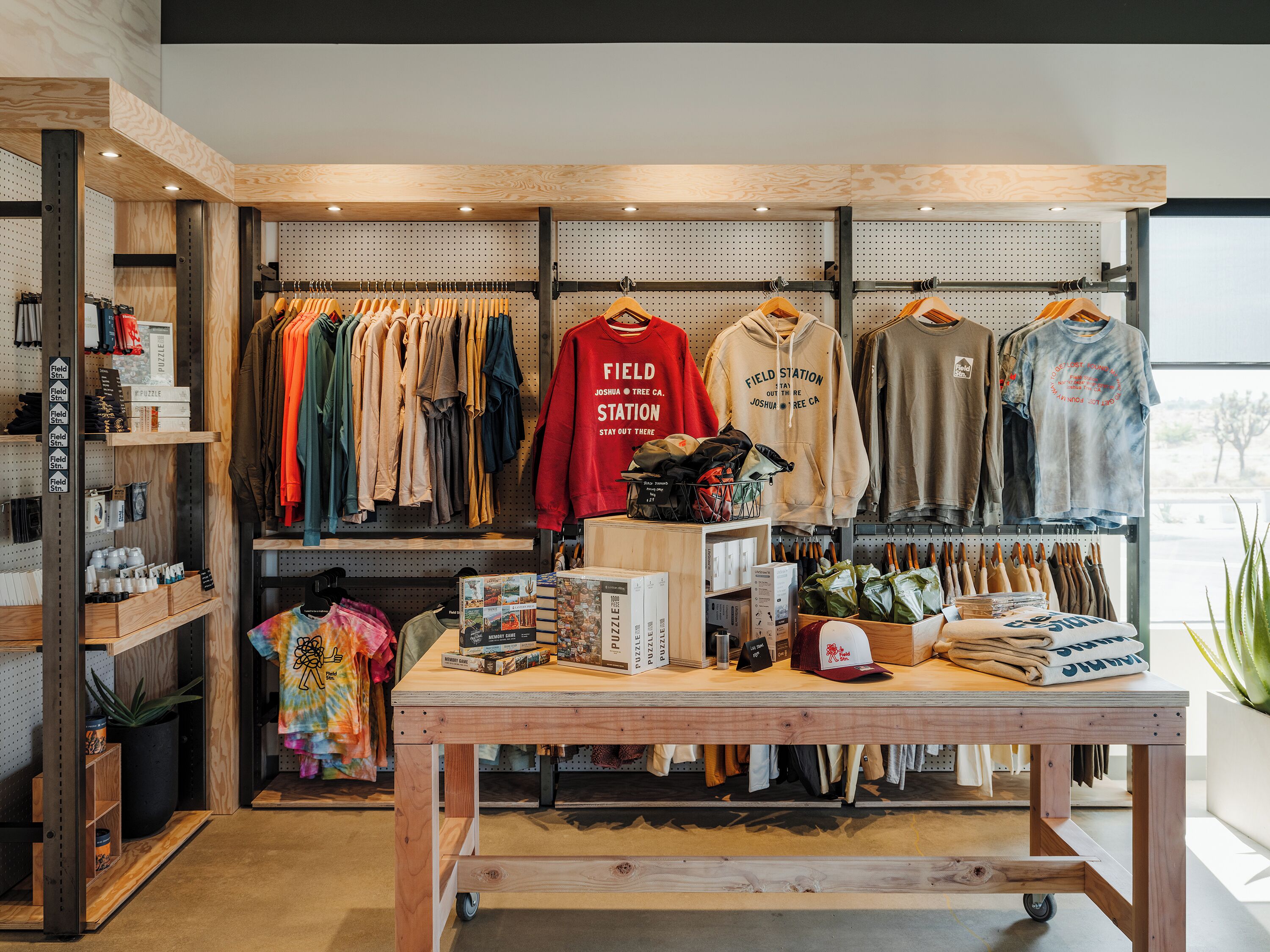A retail store with wooden shelves, clothing racks, and a central table displaying items.