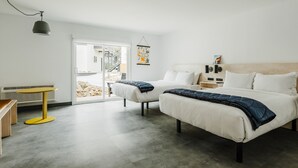 Una habitación de hotel moderna con dos camas, una mesita y un banco.
