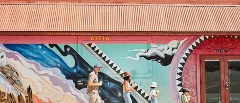 A building with a mural and the sign "JT TRADING" above.